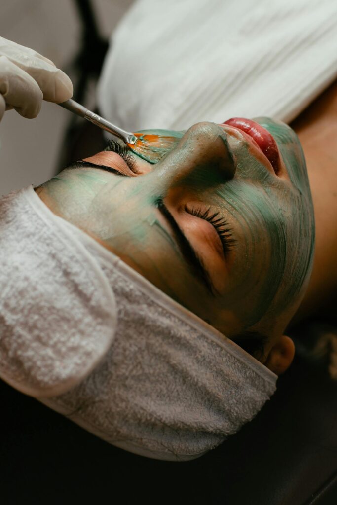 Woman receiving a soothing facial mask treatment at a spa with a brush.
